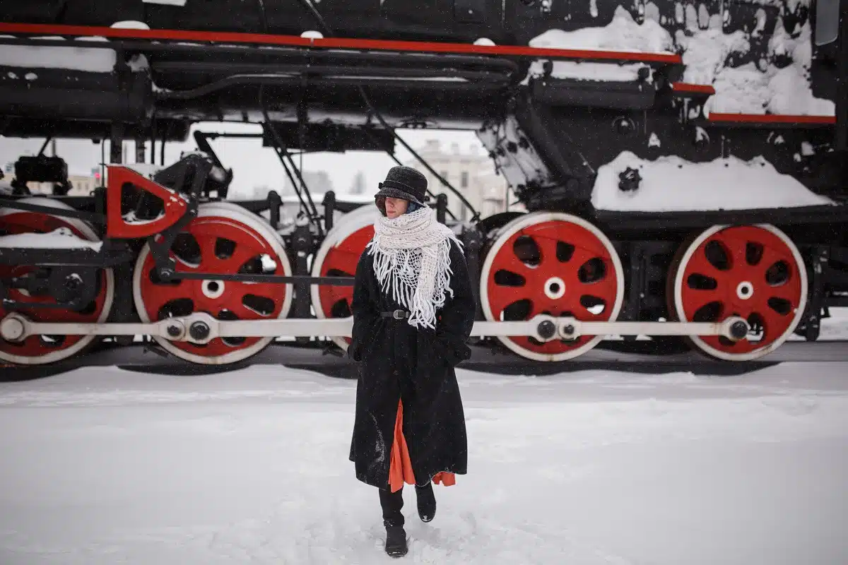 a lady walking near the old steam locomotive in winter