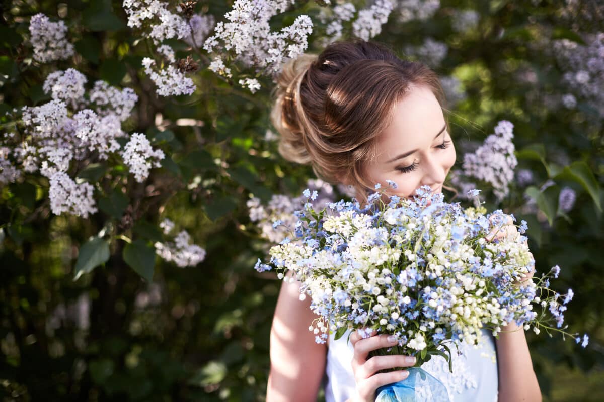 Girl with a bouquet of lilac and forget me nots in the garden