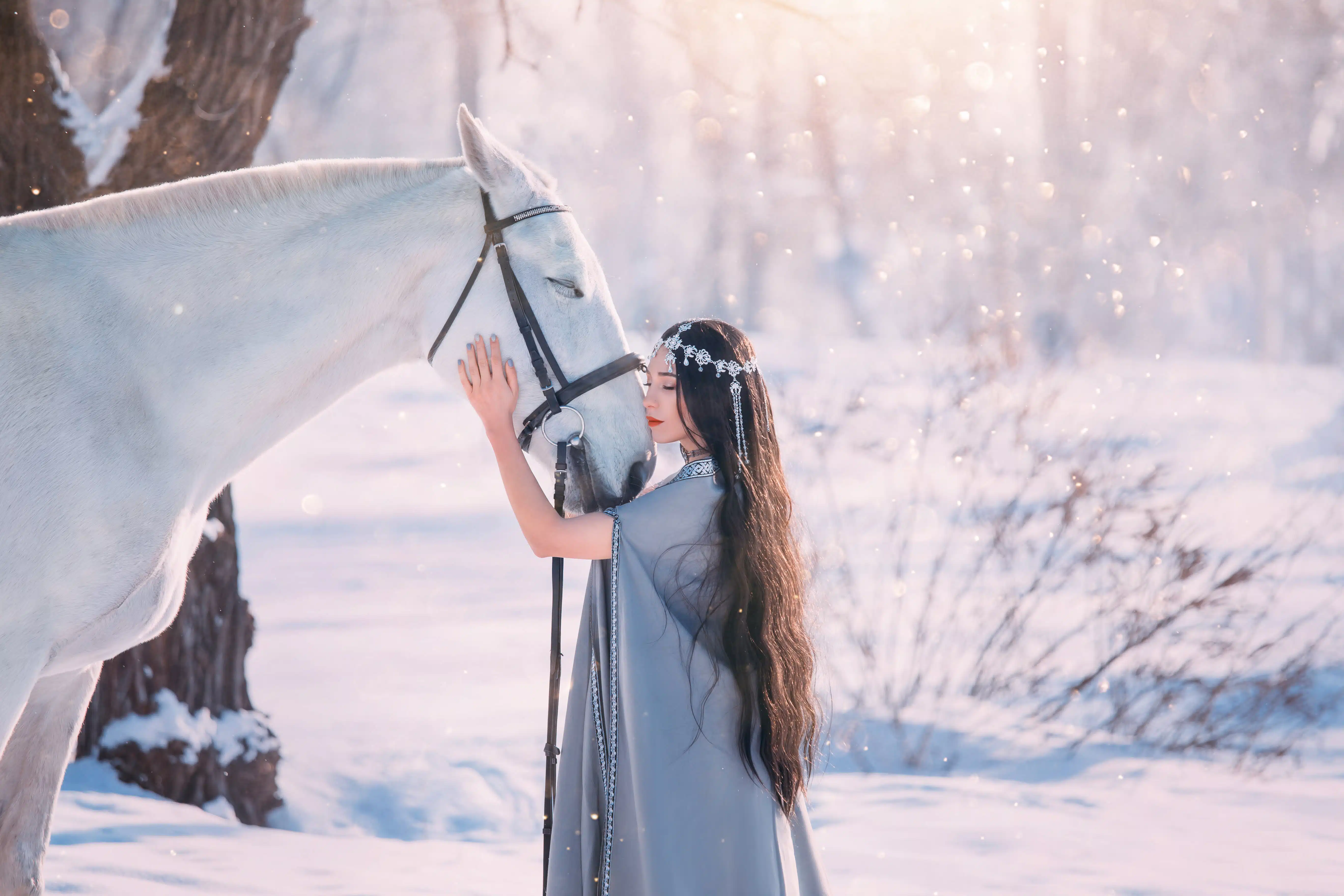 princess with long black wavy curly hair stands next to white gorgeous horse in snowy forest