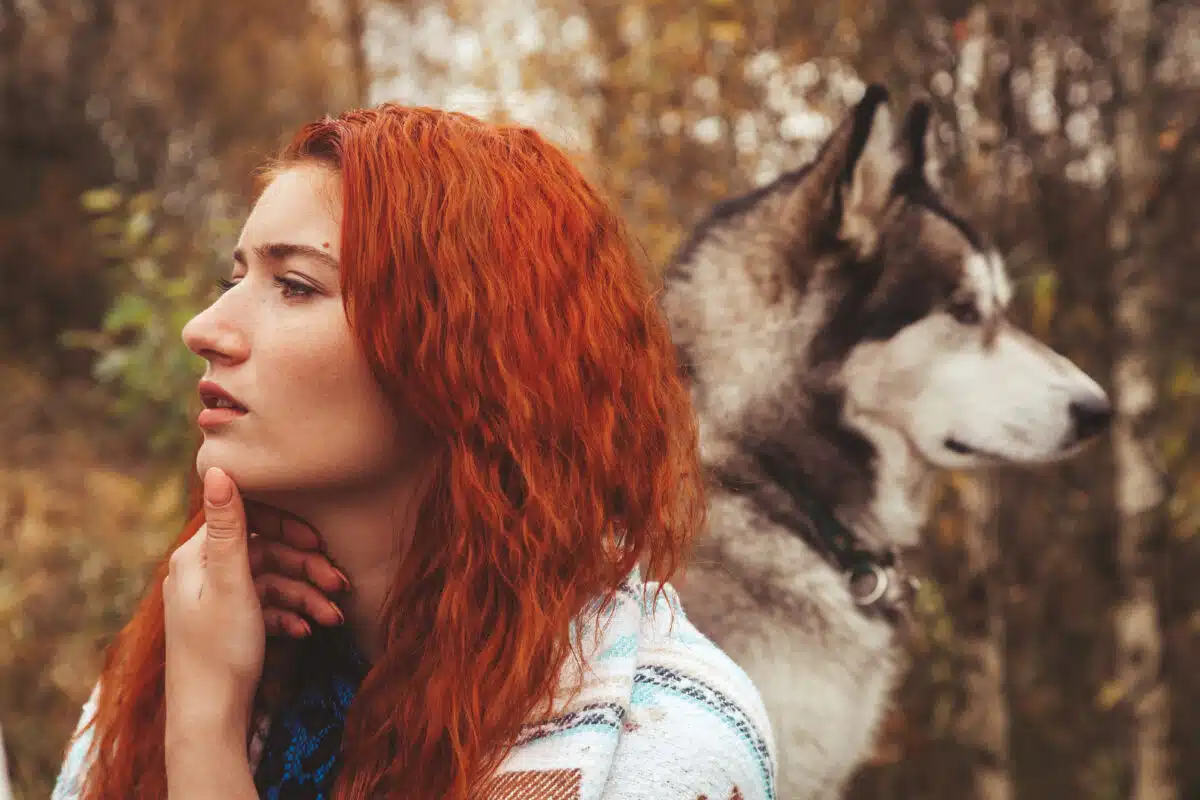 redhaired caucasian woman owner with her malamute grey big dog