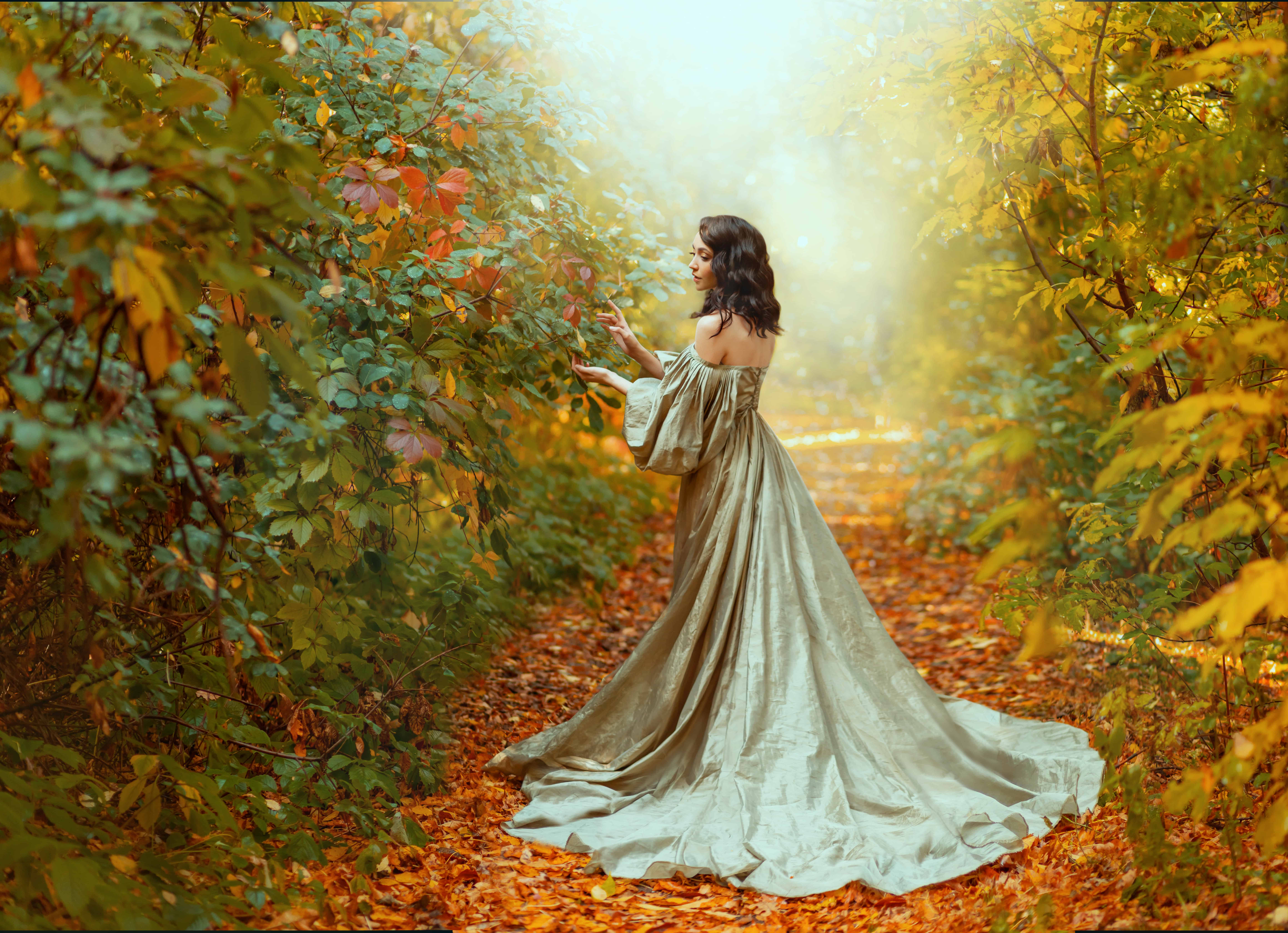 Queen woman walks in path, way mystical autumn forest. Orange foliage gothic trees mist smoke. Fantasy fairy princess girl touching leaves. Vintage long green dress, puffy sleeves. Sexy back rear view