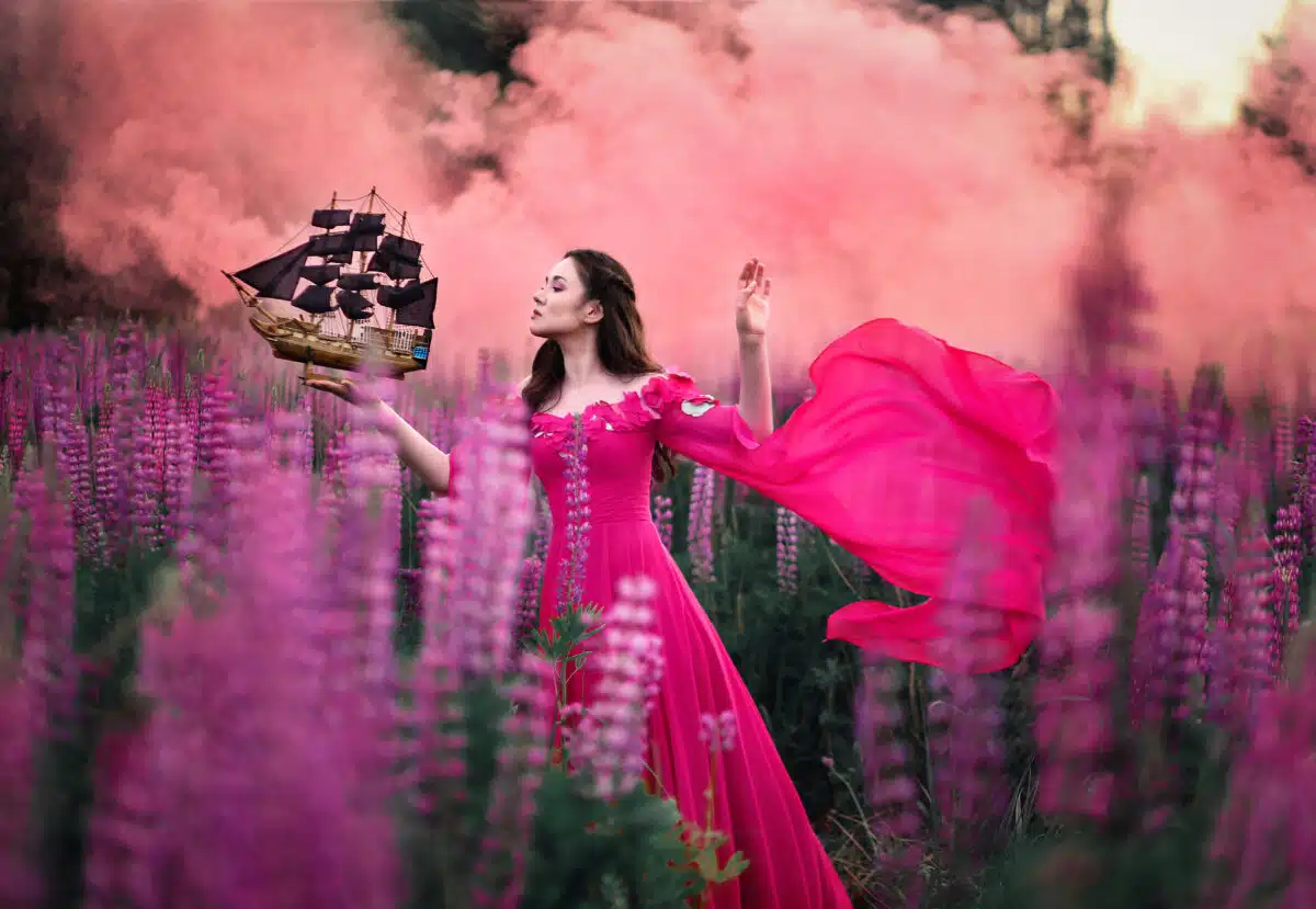 Beautiful girl in long pink dress with small ship in hand stadin