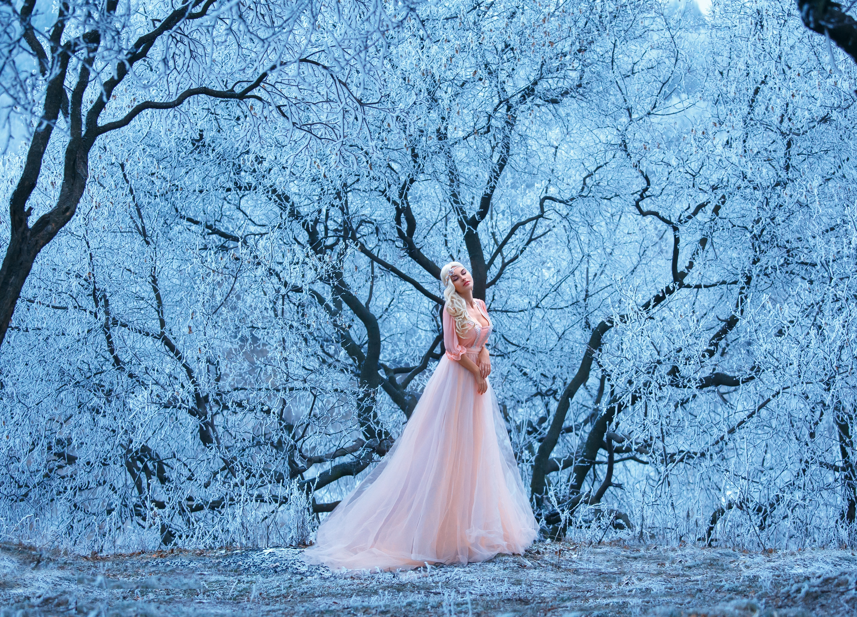 Beautiful young girl stands one among snowy trees.