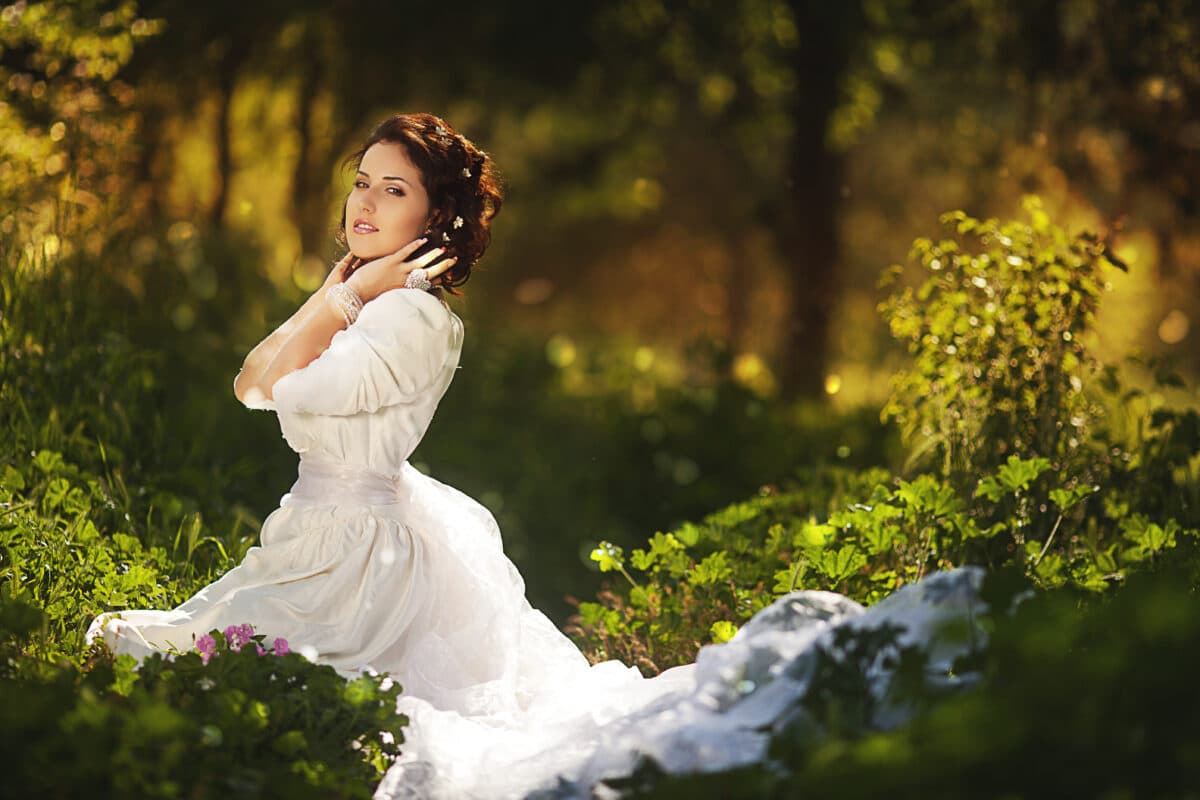 Gorgeous brunette beauty in a white vintage dress in a forest