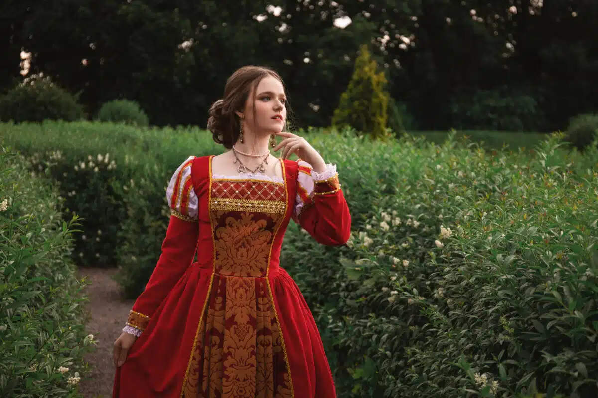 beautiful young woman in a red medieval dress is standing in the park, fantasy princess