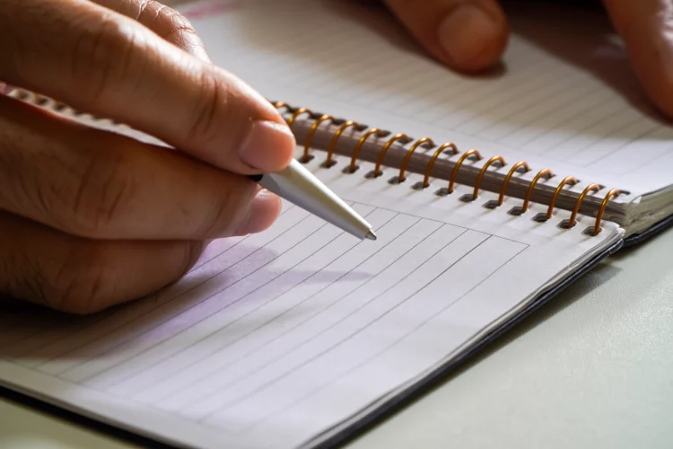 male hand with pen writing on notebook