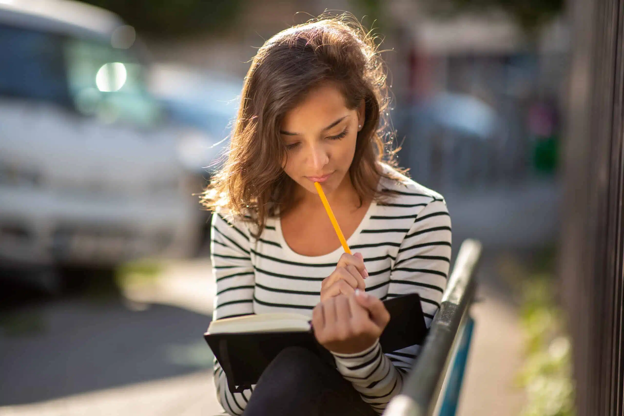 young woman sitting outside thinking of what to write
