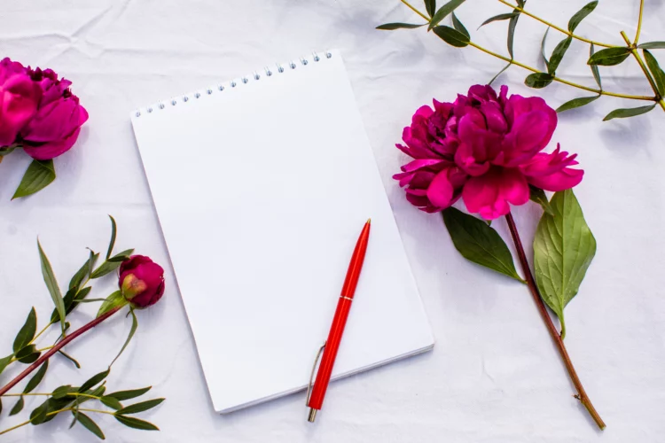 Table surface with white blank page, pen, and red roses