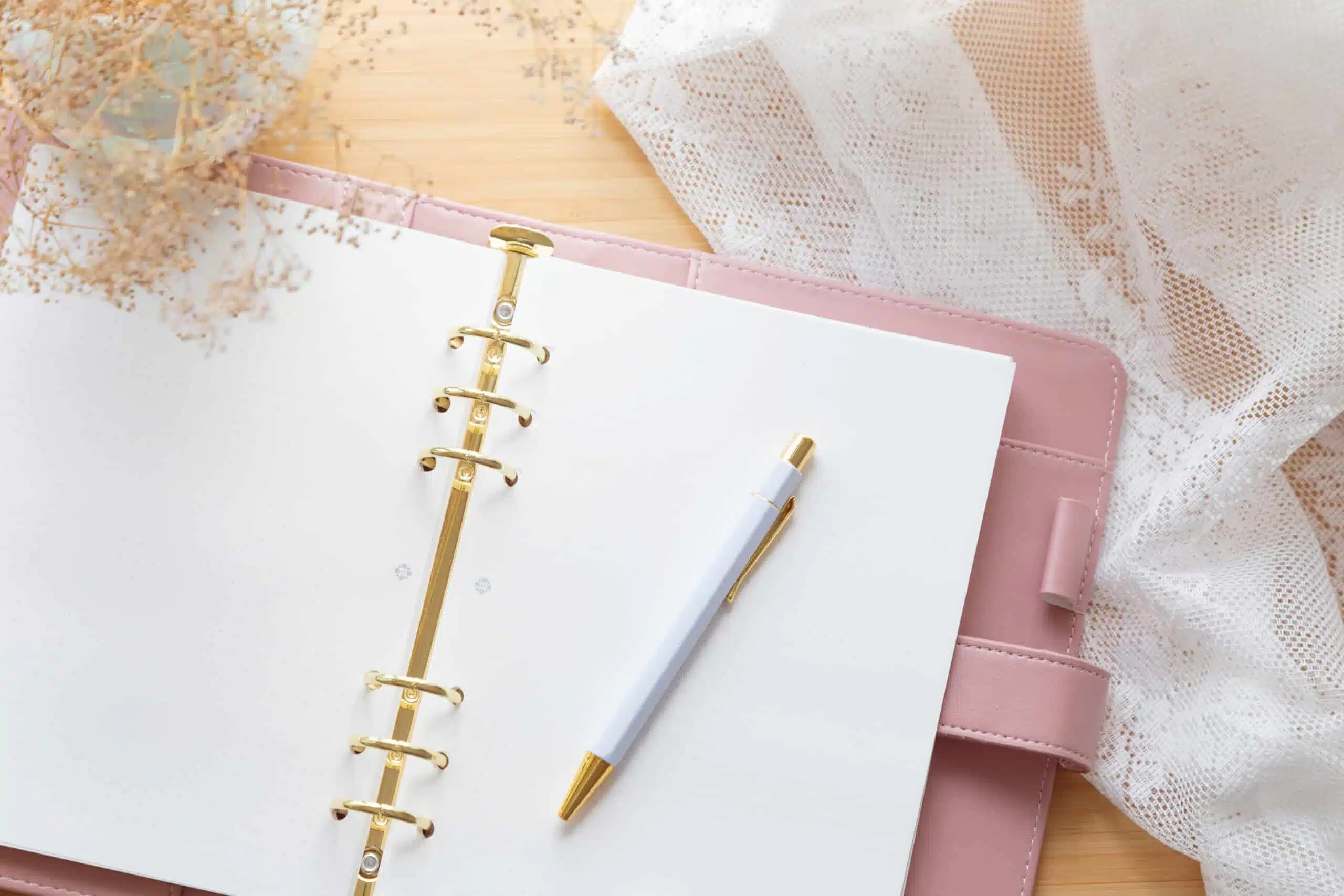 pastel pink notepad with pen and dried flower bouquet