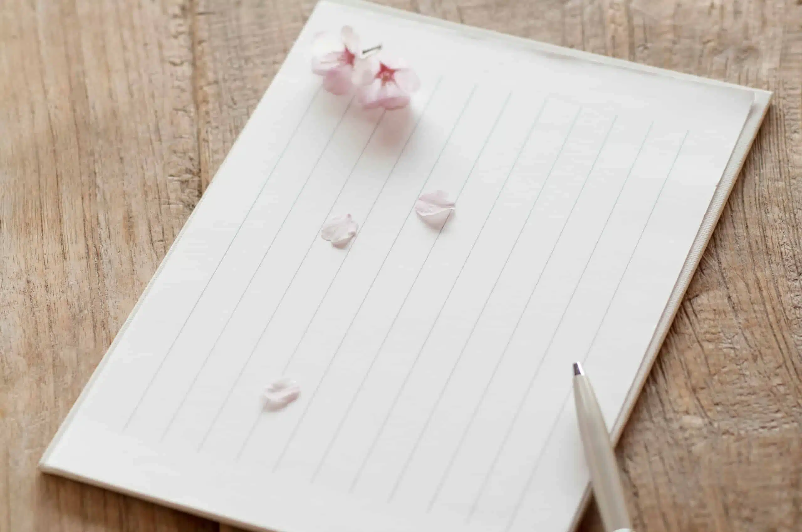asian notepad with blossoms nd pen on wood desk