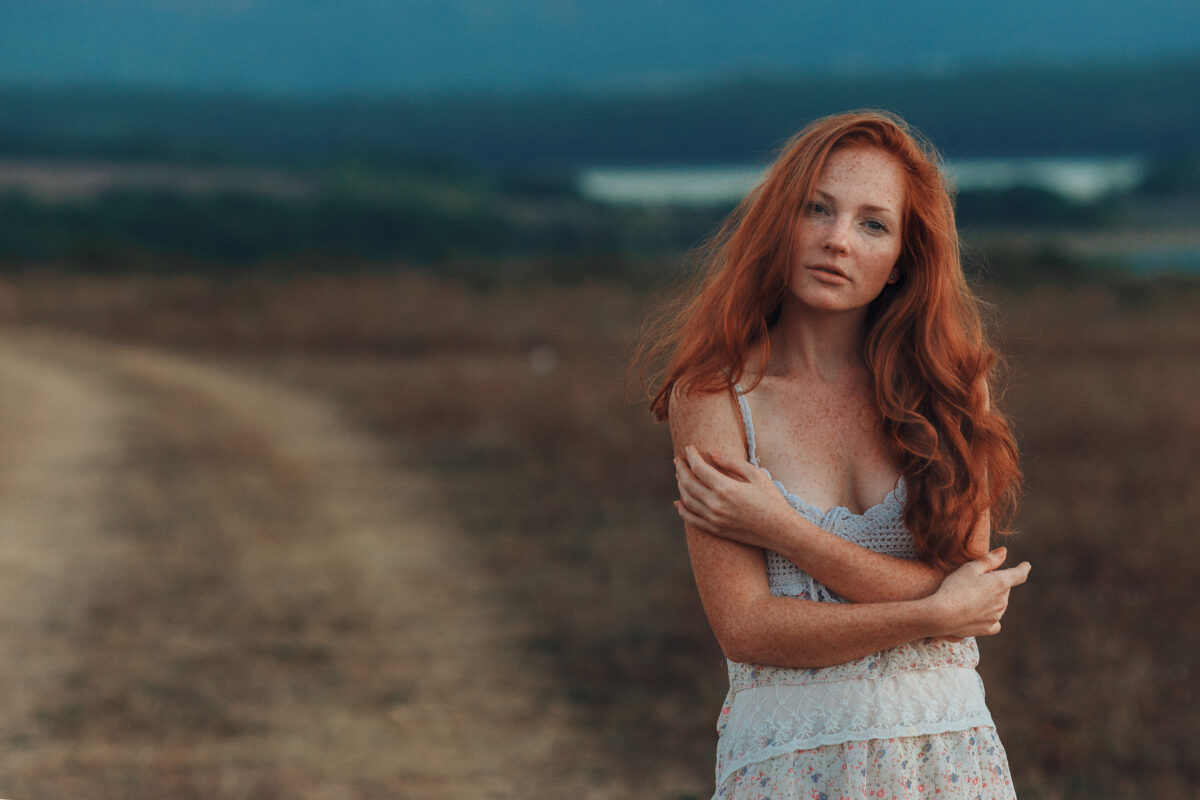 young red-haired lady with freckles on her face standing outdoor