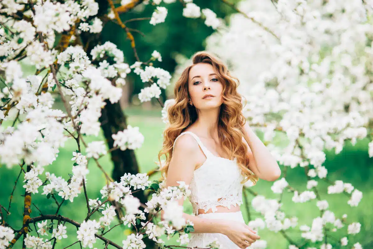 beautiful woman standing near the blooming apple trees in the garden