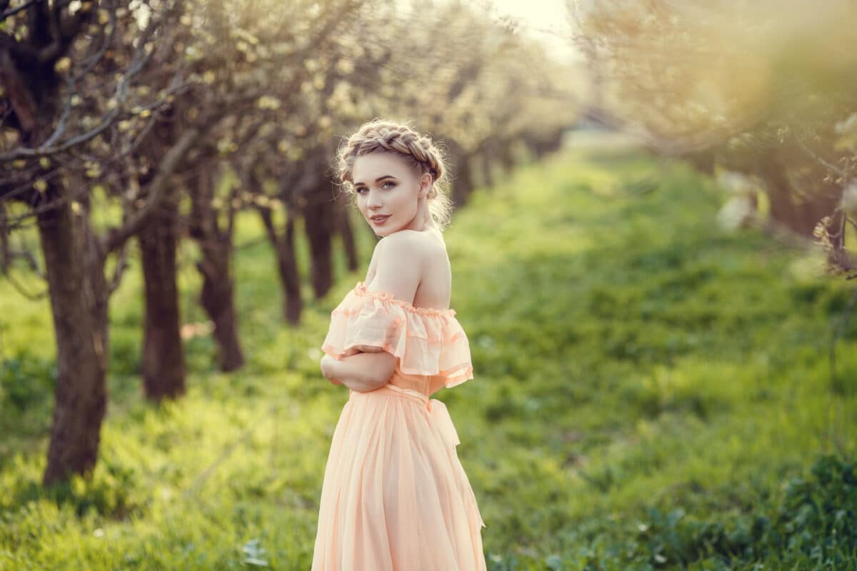 Beautiful young girl in an old dress in a pear-blossoming garden