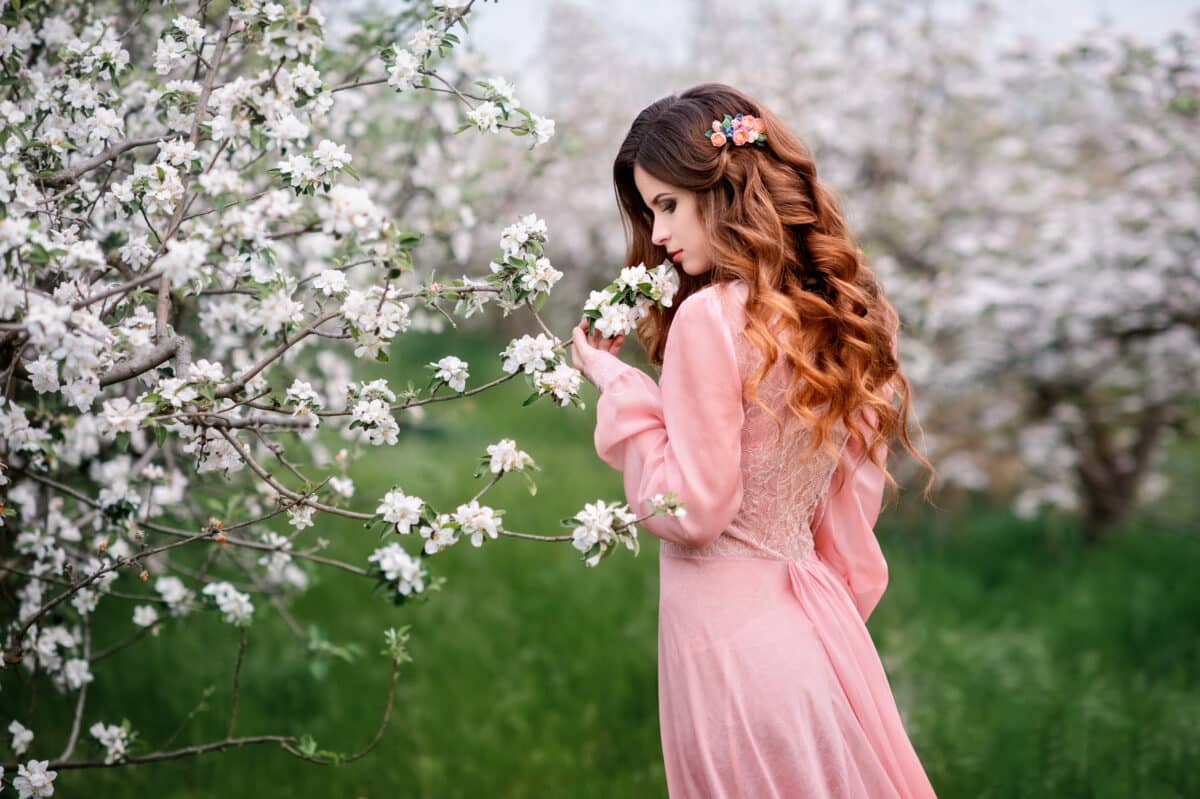 a pretty young woman in a beautiful dress in a blooming spring garden