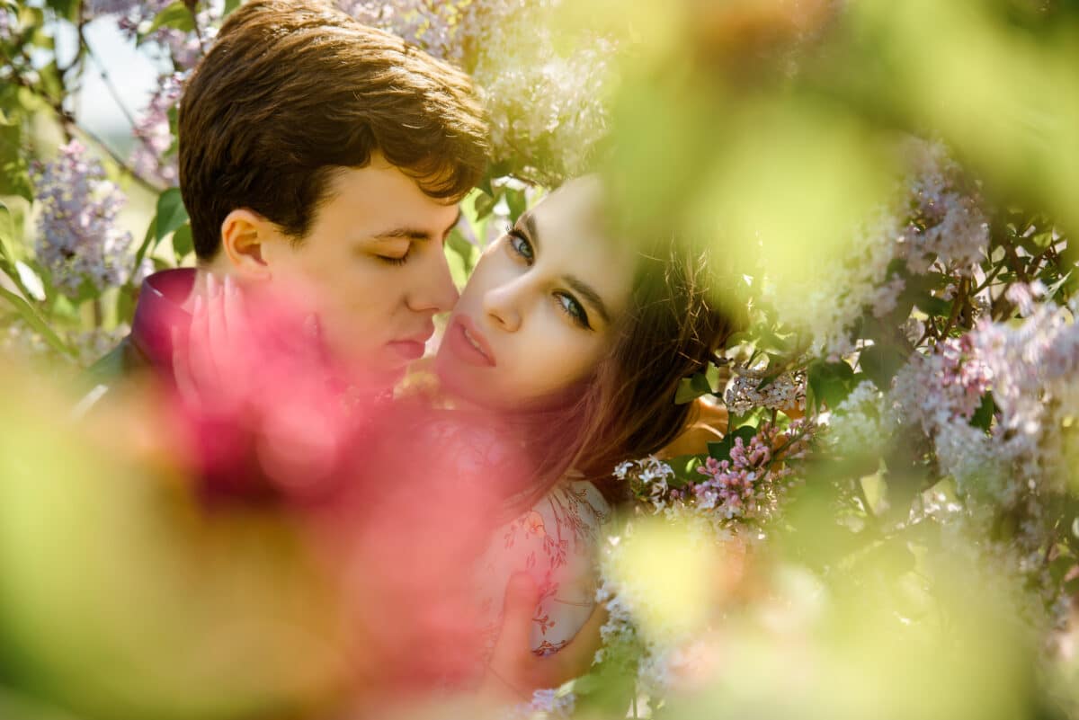 young beautiful couple hugging amid lilac flowers