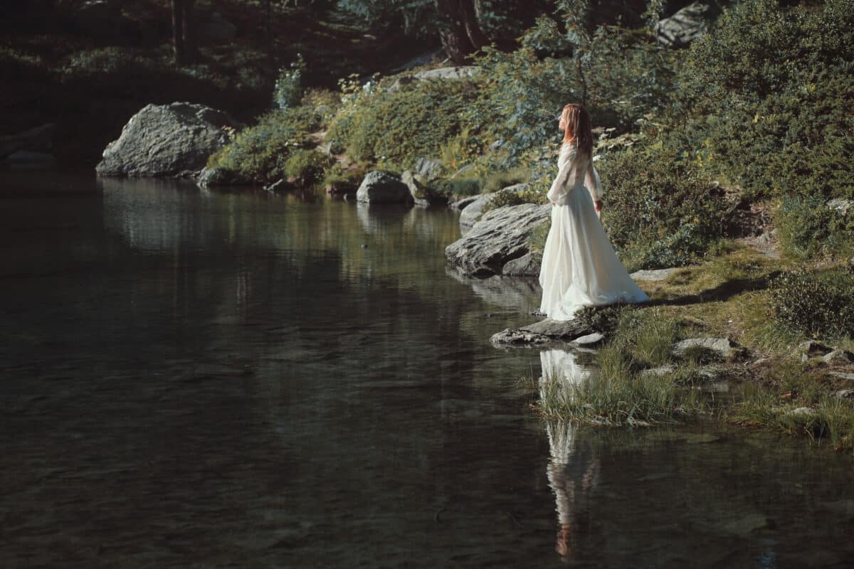 romantic woman in white dress standing by the lake