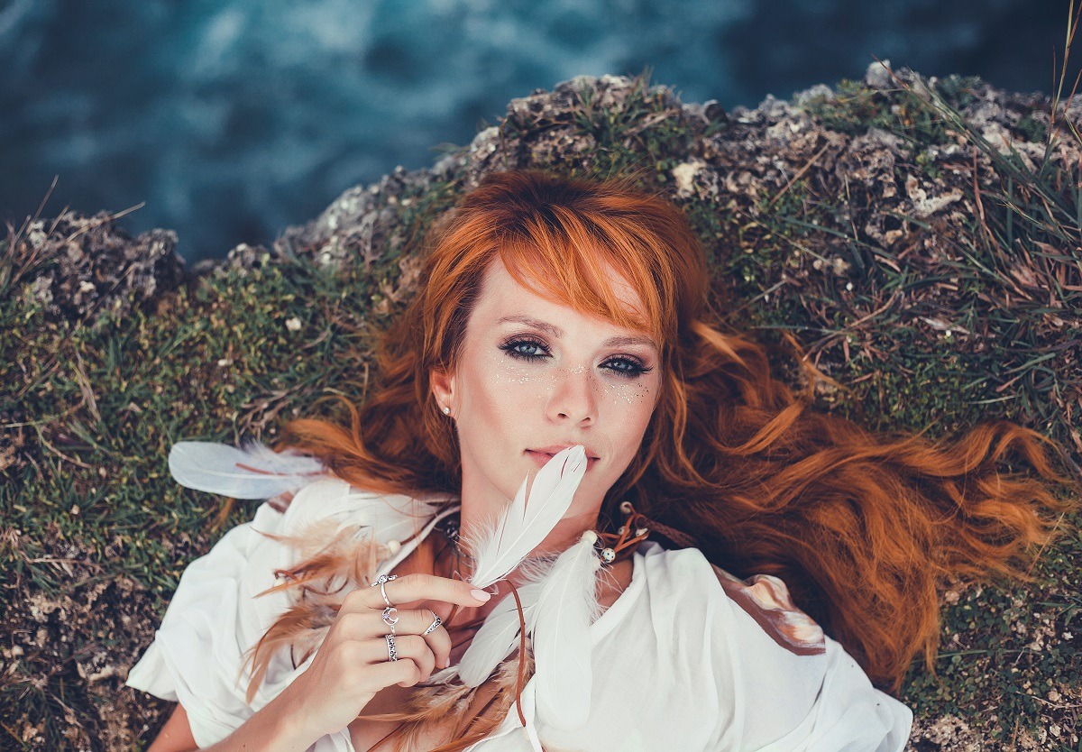 Pretty redhead lying on the ground in boho style.