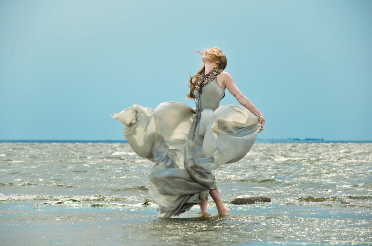 woman in a gray silk dress, fanned by the wind on the ocean