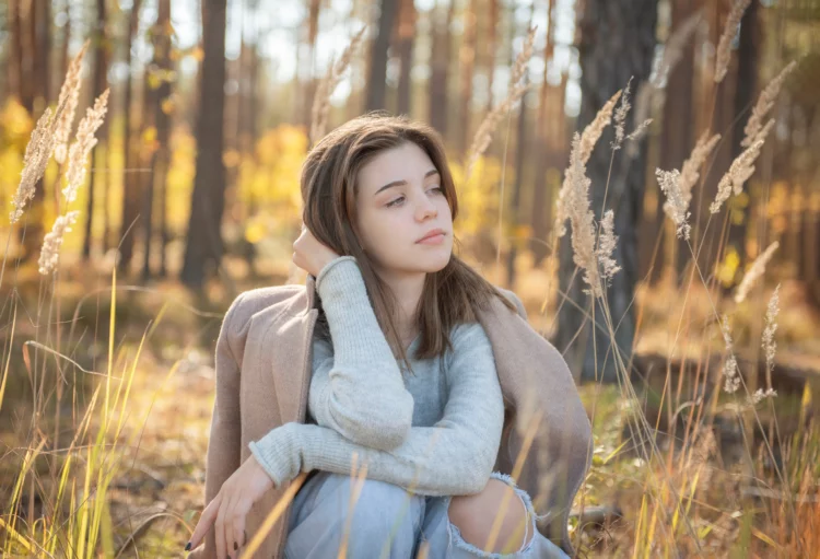 melancholic young lady sitting in the woods in autumn