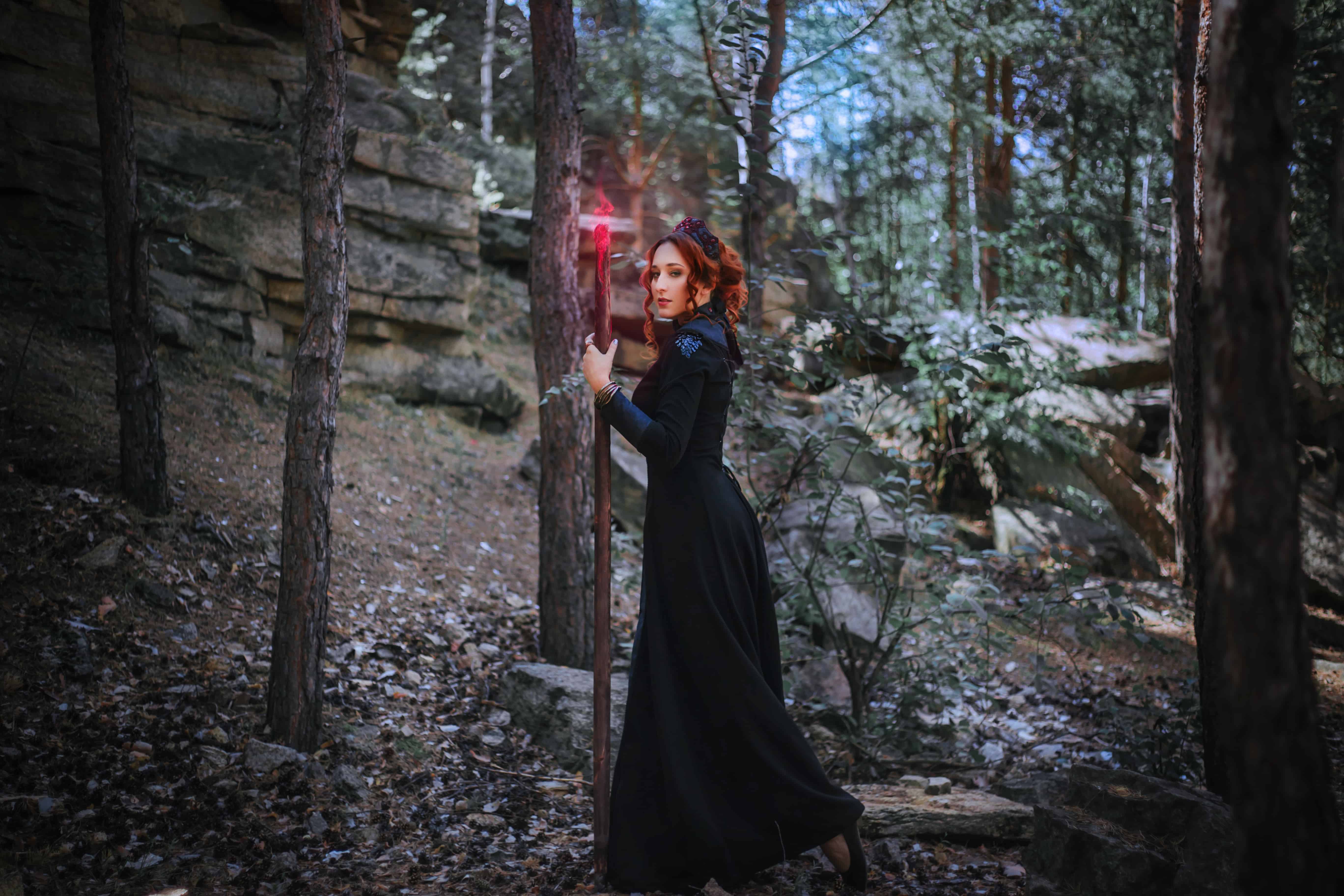 Evil witch with a staff in the forest. 